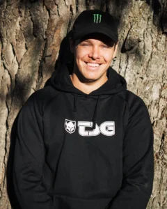 Man med svart hoodie och keps vid träd