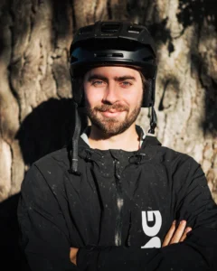 Man med cykelhjälm framför träd.